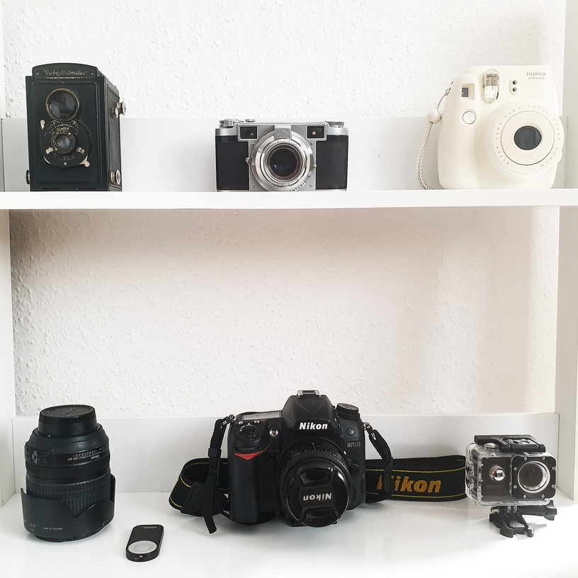 Digital and analog cameras on white shelves